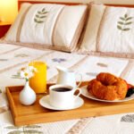 Tray with breakfast on a bed in a hotel room, showing the concept of marketing a lodge